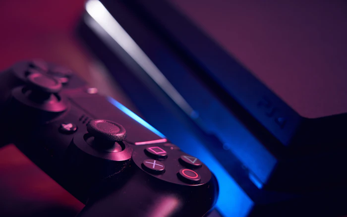 PlayStation controller and console in blue and magenta light