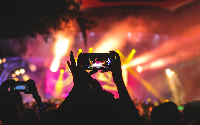Phone recording a concert surrounded by stage lights